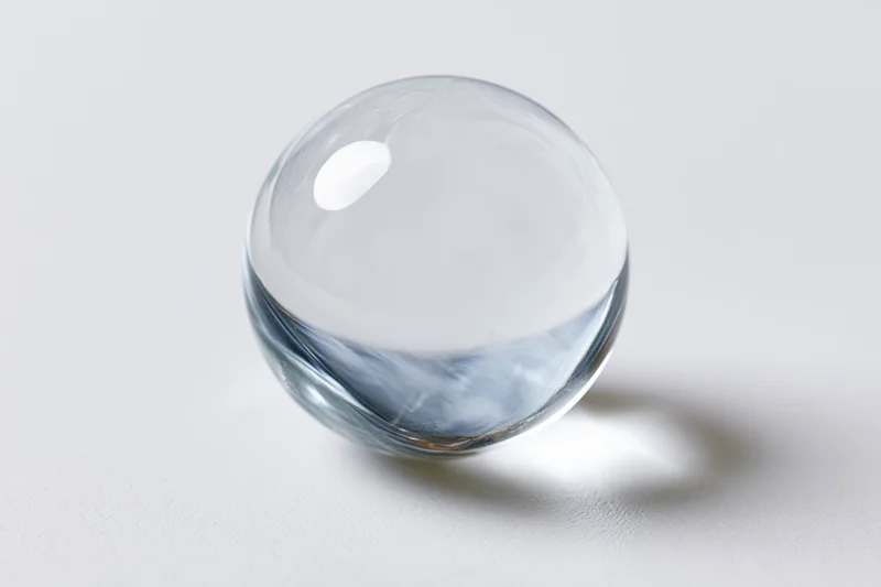 Clear glass sphere resting on plain white surface