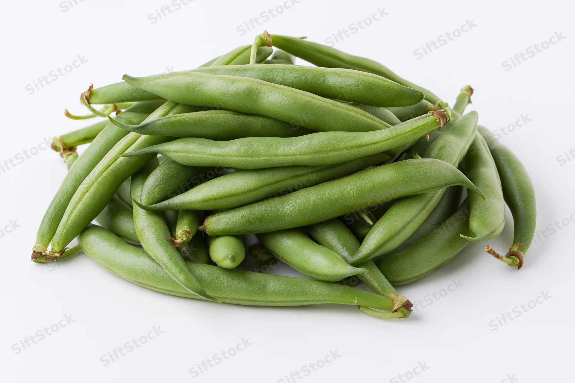 Loose pile of fresh green beans arranged in a casual heap on white background