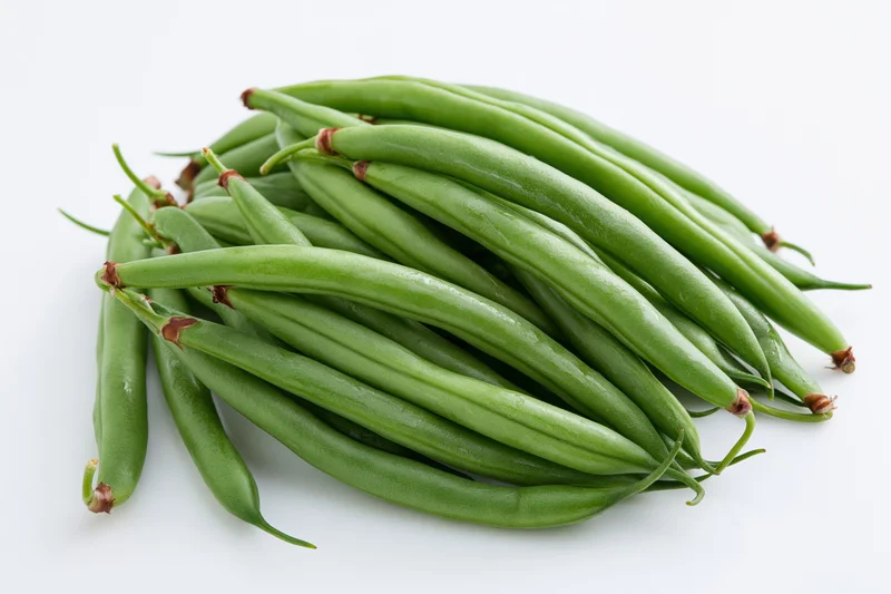Fresh green beans arranged in a casual heap on white background