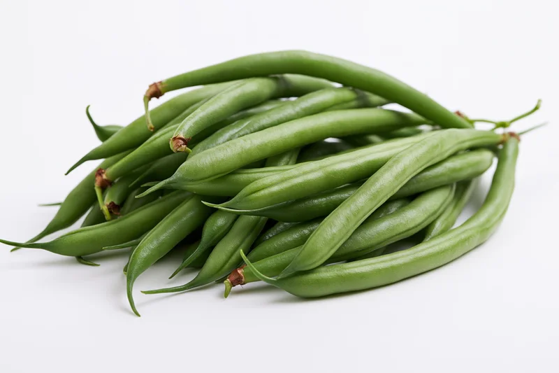 Fresh green beans arranged in a loose heap on a white background