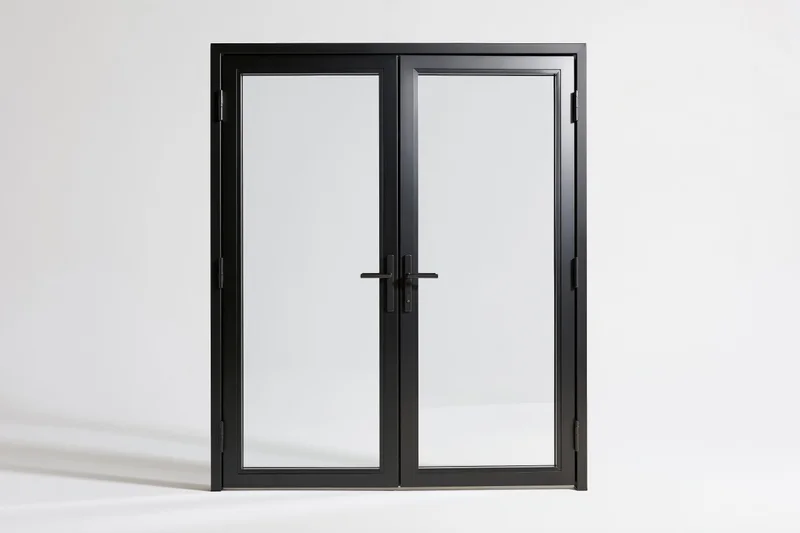 Black steel-framed french doors with full-length glass panels standing in a white studio space