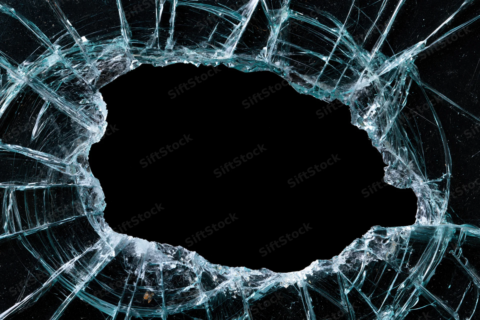 Shattered glass pane with large oval hole and radiating cracks against black background