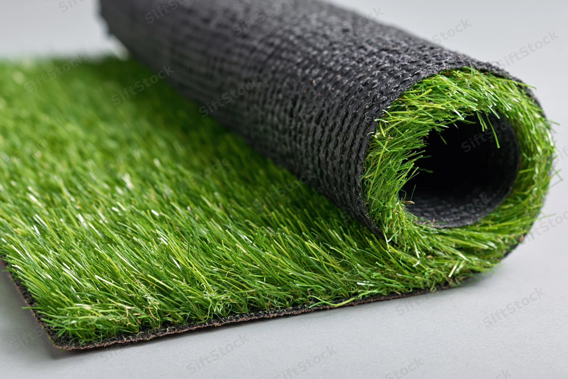 Roll of artificial grass turf partially unrolled on a flat surface