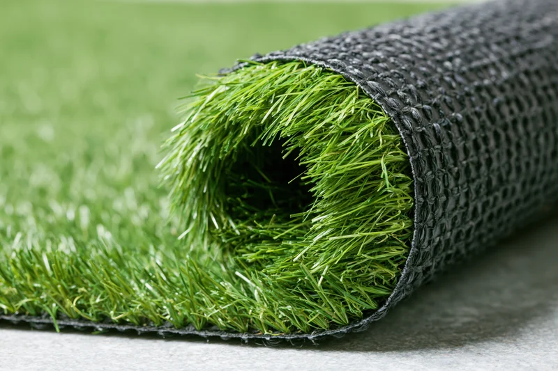 Roll of artificial grass turf partially unrolled on a flat surface