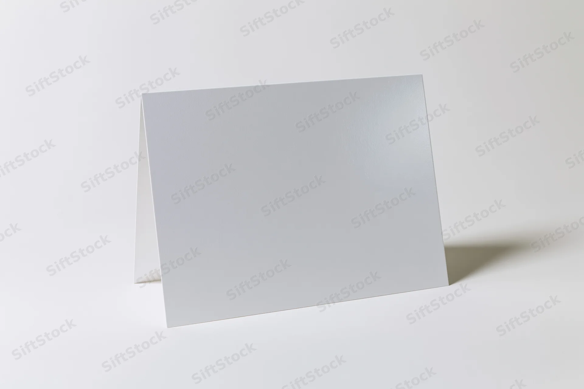 Blank white rectangular card folded and standing upright on a plain surface