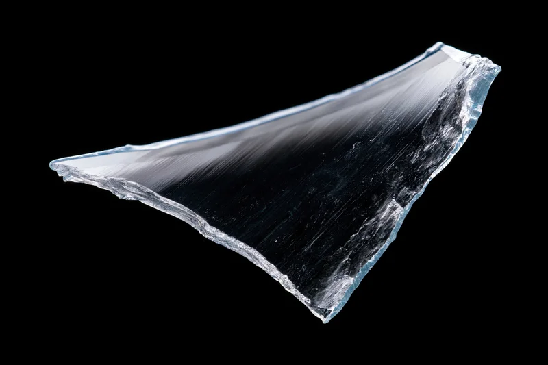 Jagged shard of broken glass floating against a pure black background