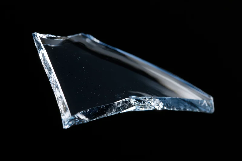 Jagged shard of broken glass floating against a pure black background