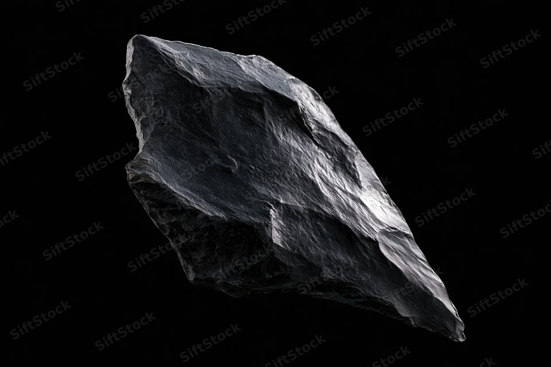 Dark obsidian stone fragment floating against black background
