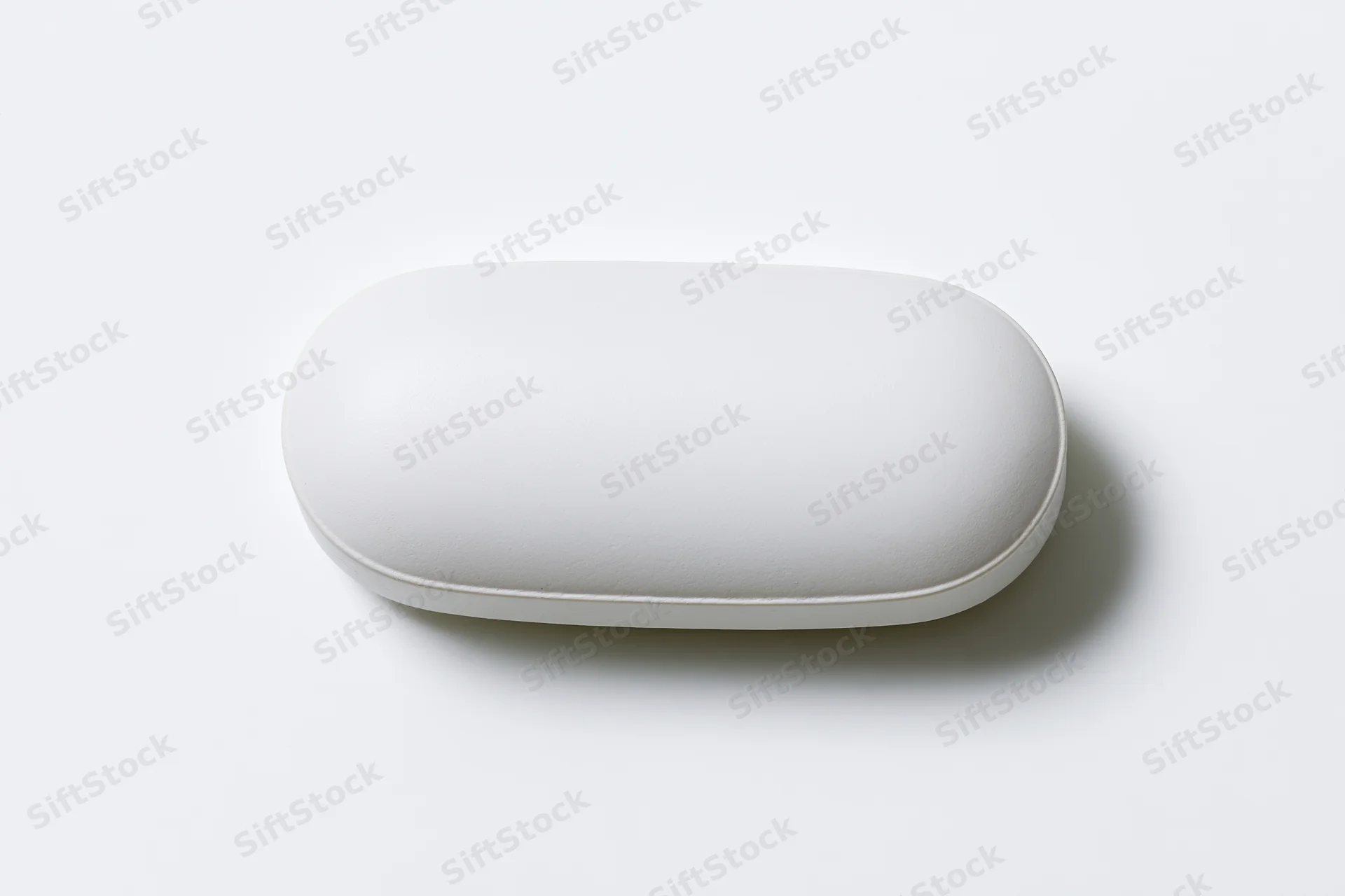 White oval pill capsule lying flat centered on plain white surface