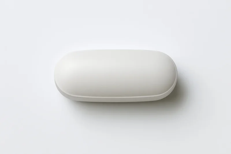 White oval pill capsule lying flat centered on plain white surface