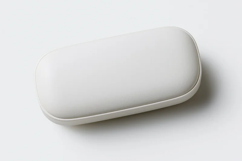 White oval pill capsule lying flat centered on plain white surface