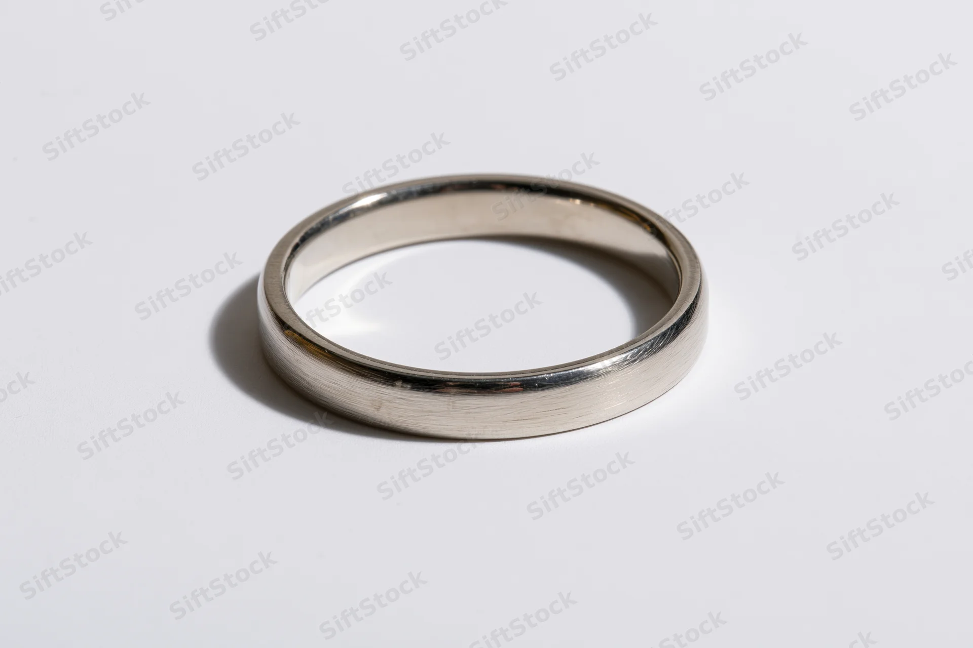 Thin polished silver ring lying flat on white surface