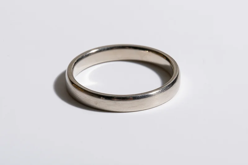 Thin polished silver ring lying flat on white surface