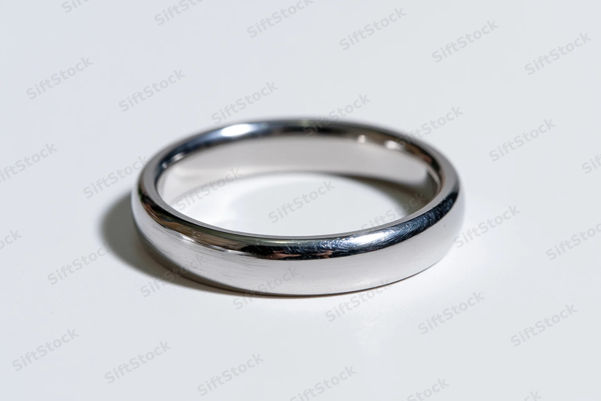 Thin polished silver ring lying flat on white surface