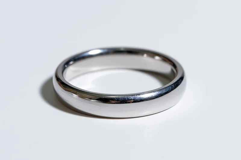 Thin polished silver ring lying flat on white surface
