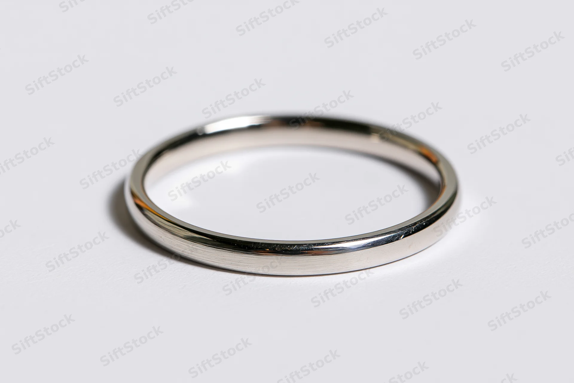 Thin polished metal ring lying flat on white surface