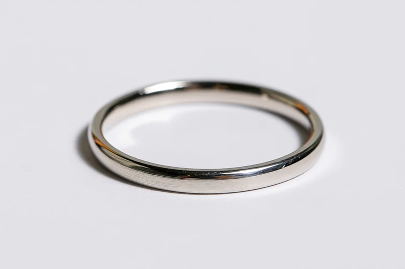 Thin polished metal ring lying flat on white surface