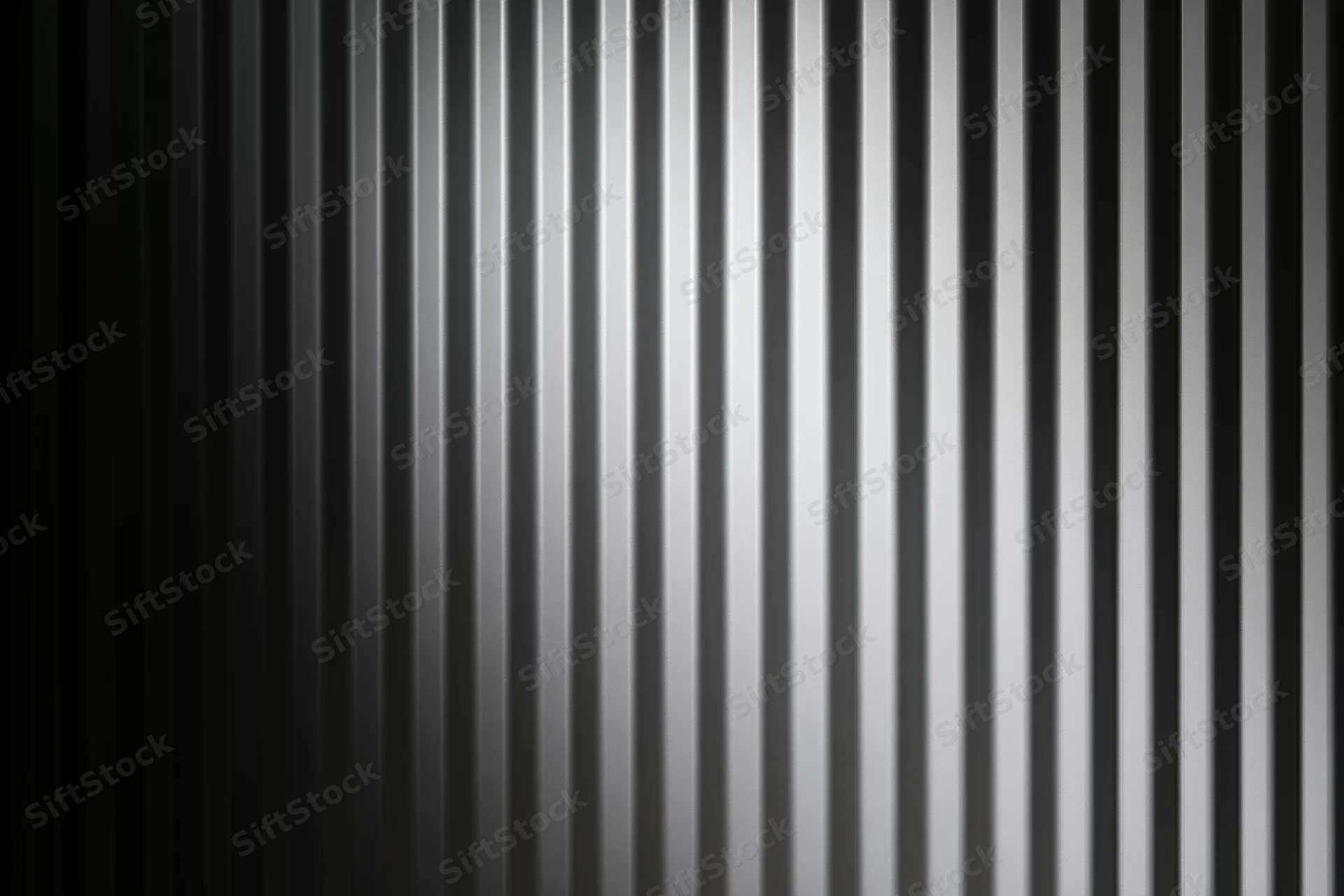 Close-up of a corrugated metal surface with vertical ribs and a gradient of gray tones
