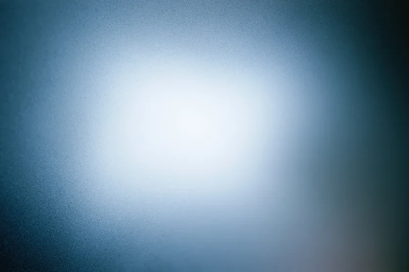 Frosted glass surface with diffused light creating a soft blue gradient background