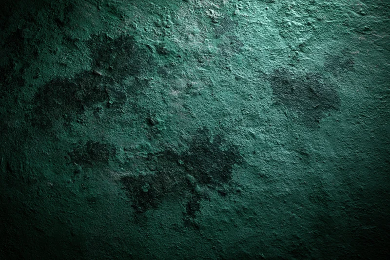 Textured green surface filling the frame with rough uneven pattern and dark shadows