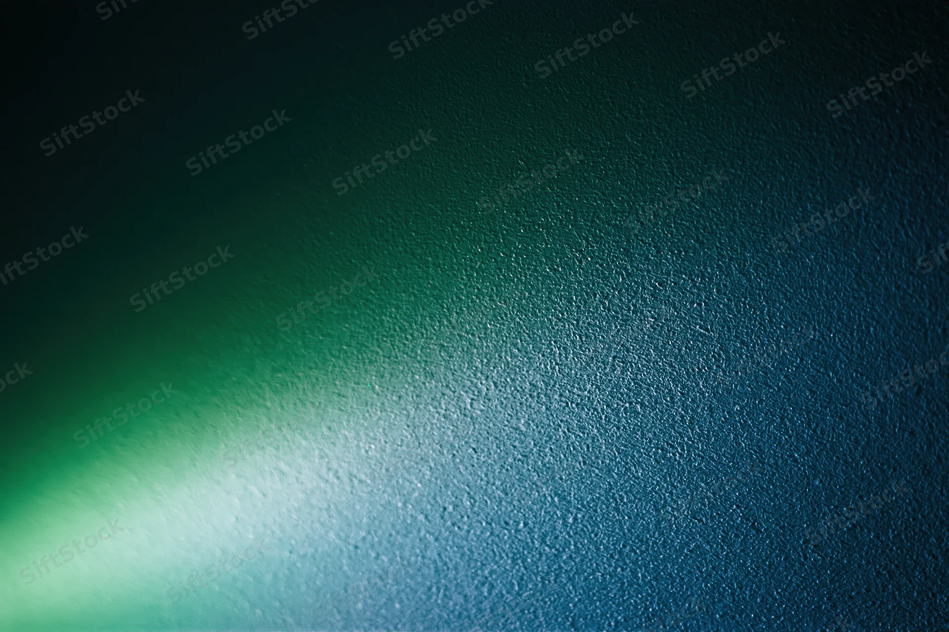 Abstract textured surface with soft glowing green light transitioning to blue