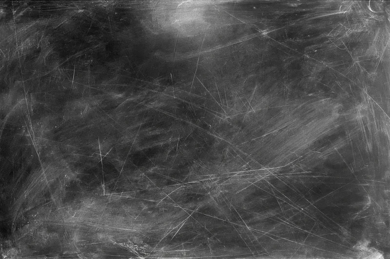 Aged black chalkboard surface covered in fine scratches and dust