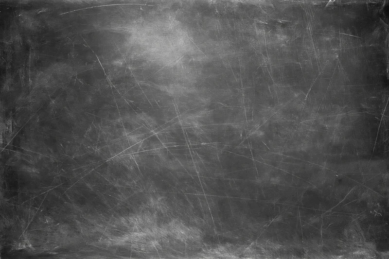 Aged black chalkboard surface covered in fine scratches and dust, showing wear and residue from use
