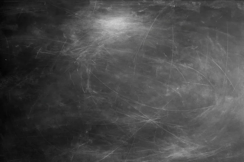 Aged black chalkboard surface covered in fine scratches and dust residue