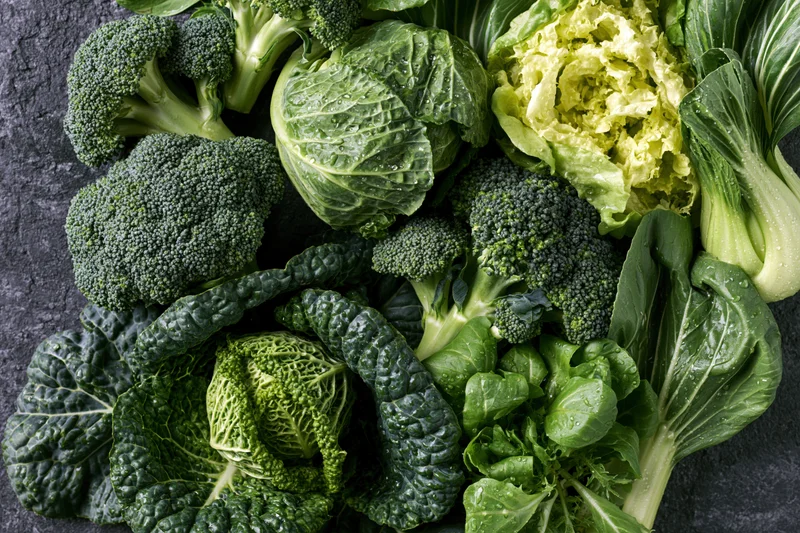 Assorted green vegetables arranged on dark surface in flat lay composition