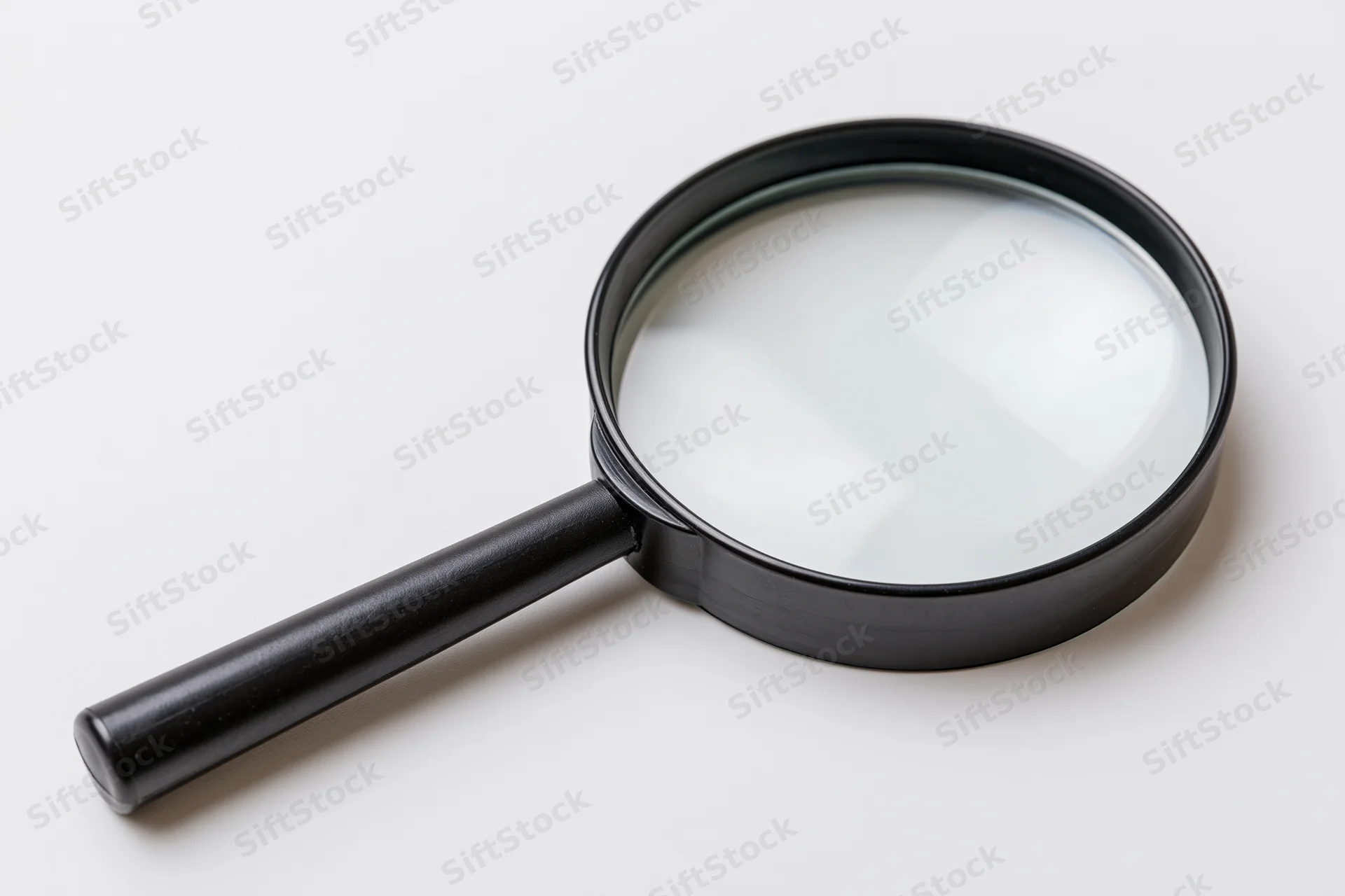 Black magnifying glass with glossy lens resting diagonally on white surface