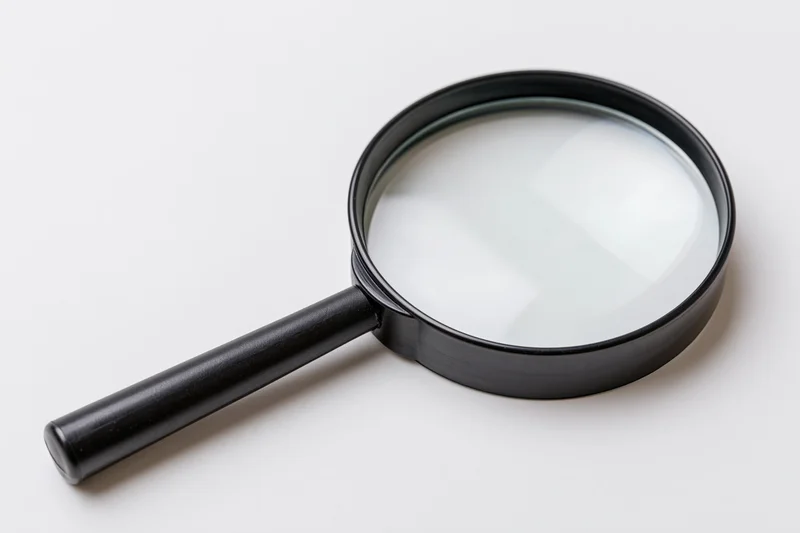Black magnifying glass with glossy lens resting diagonally on white surface