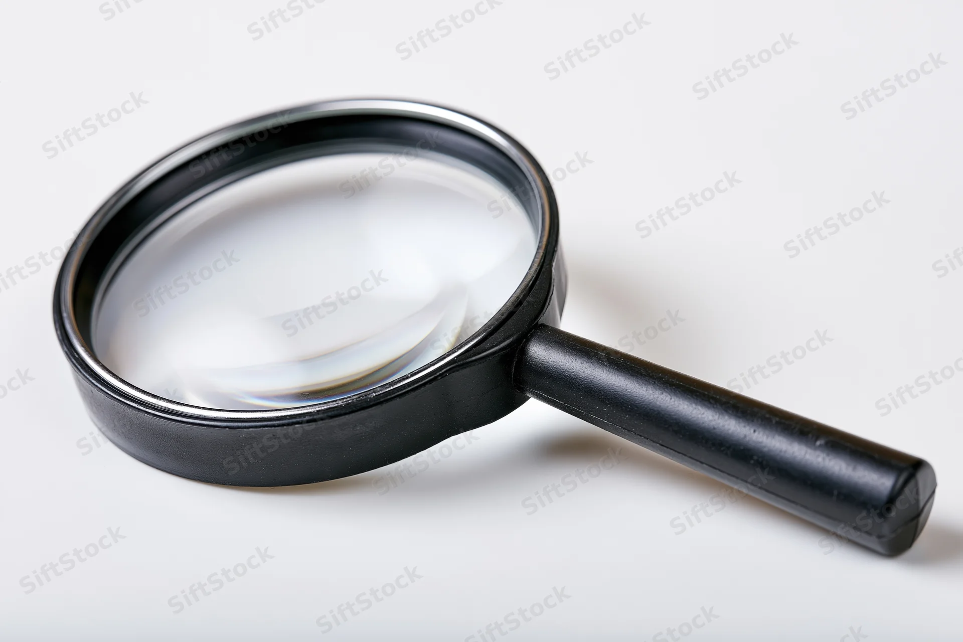 Black magnifying glass with glossy lens resting diagonally on white surface