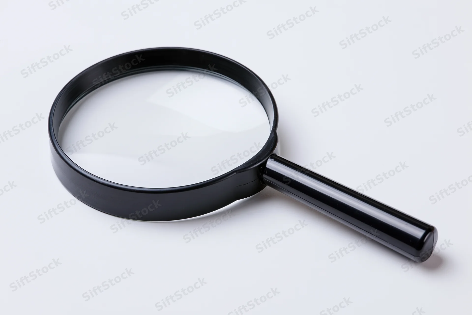 Black magnifying glass with glossy plastic handle resting on white surface
