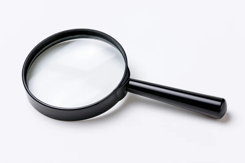 Black magnifying glass with glossy plastic handle resting on white surface