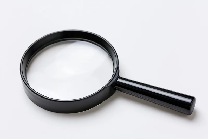 Black magnifying glass with glossy plastic handle resting on white background
