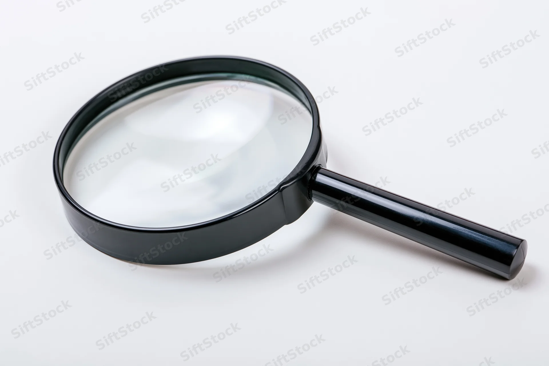 Black magnifying glass with glossy plastic handle resting on white surface