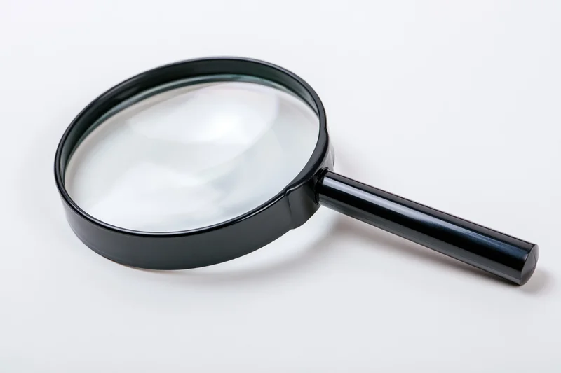Black magnifying glass with glossy plastic handle resting on white surface