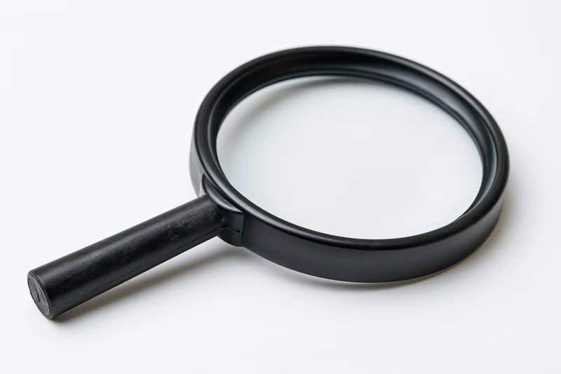 Black plastic magnifying glass with cylindrical handle resting on white surface