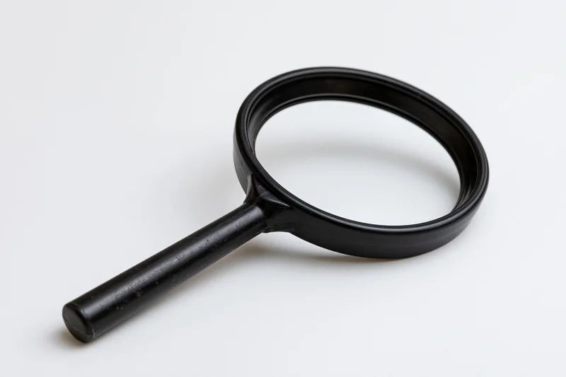 Black plastic magnifying glass with cylindrical handle resting on white surface