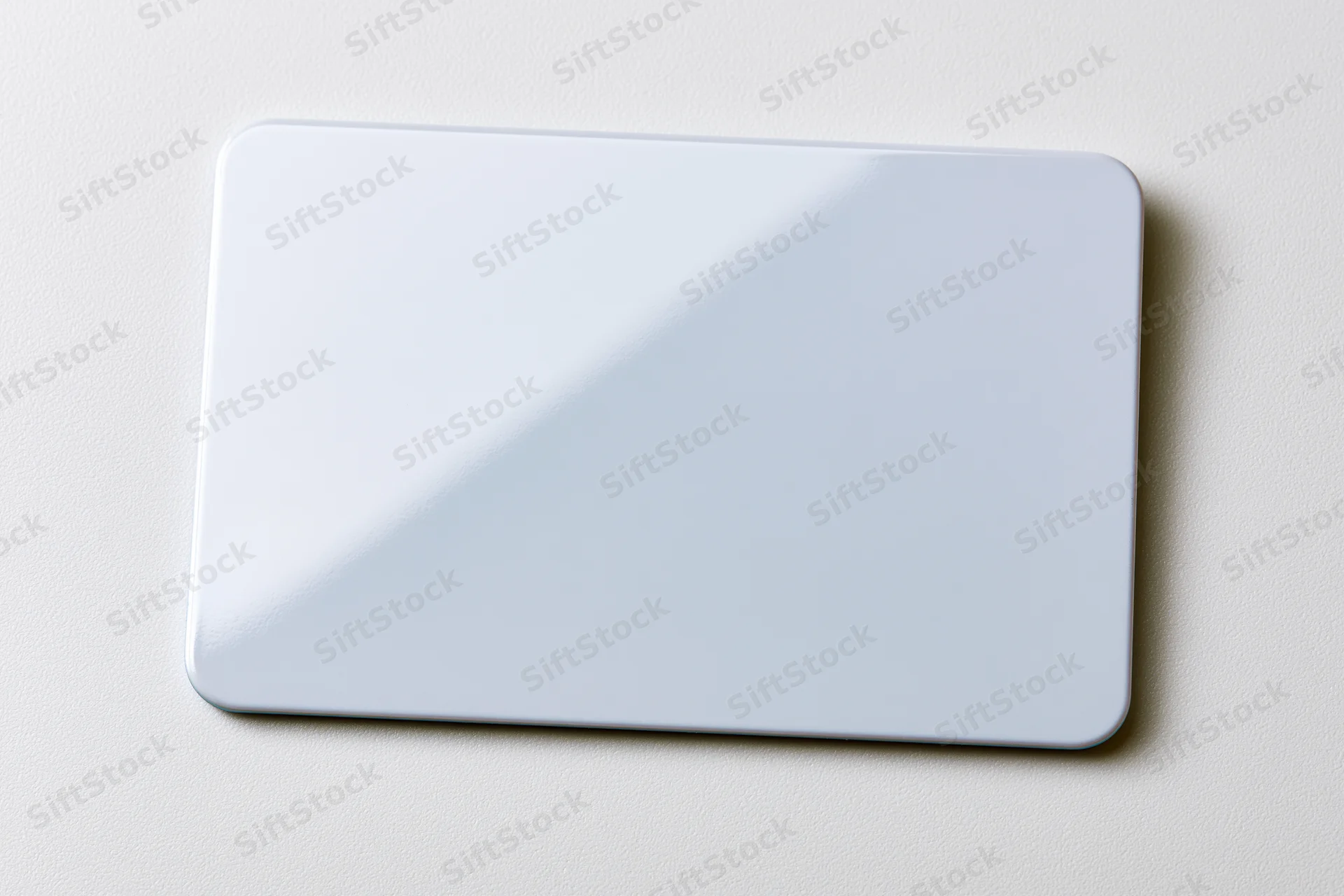 Blank white plastic card lying flat on a white surface center