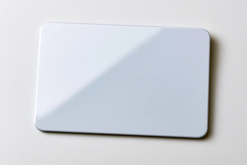 Blank white plastic card lying flat on a white surface center