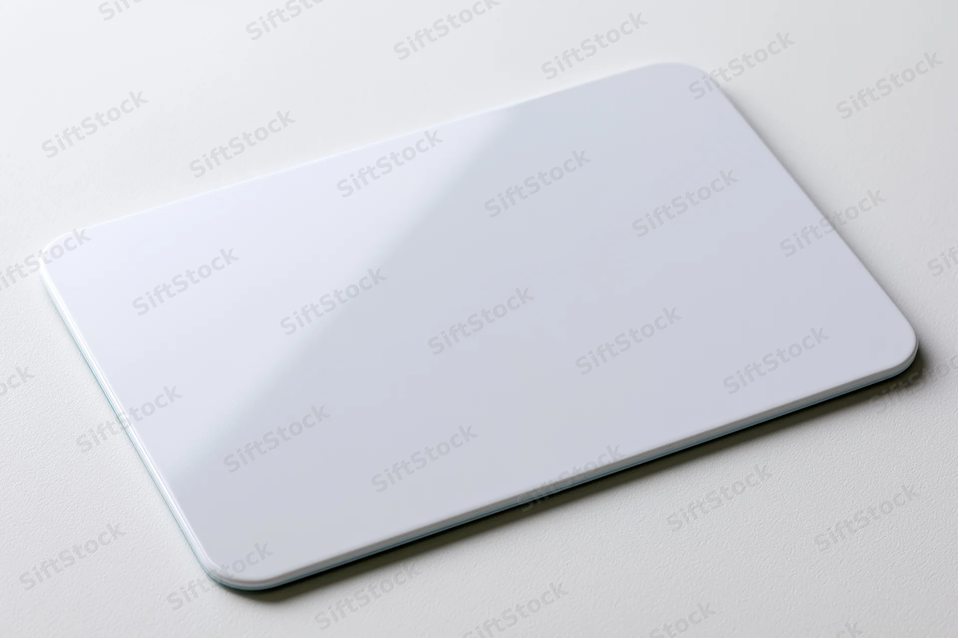 Blank white plastic card lying flat on a white surface