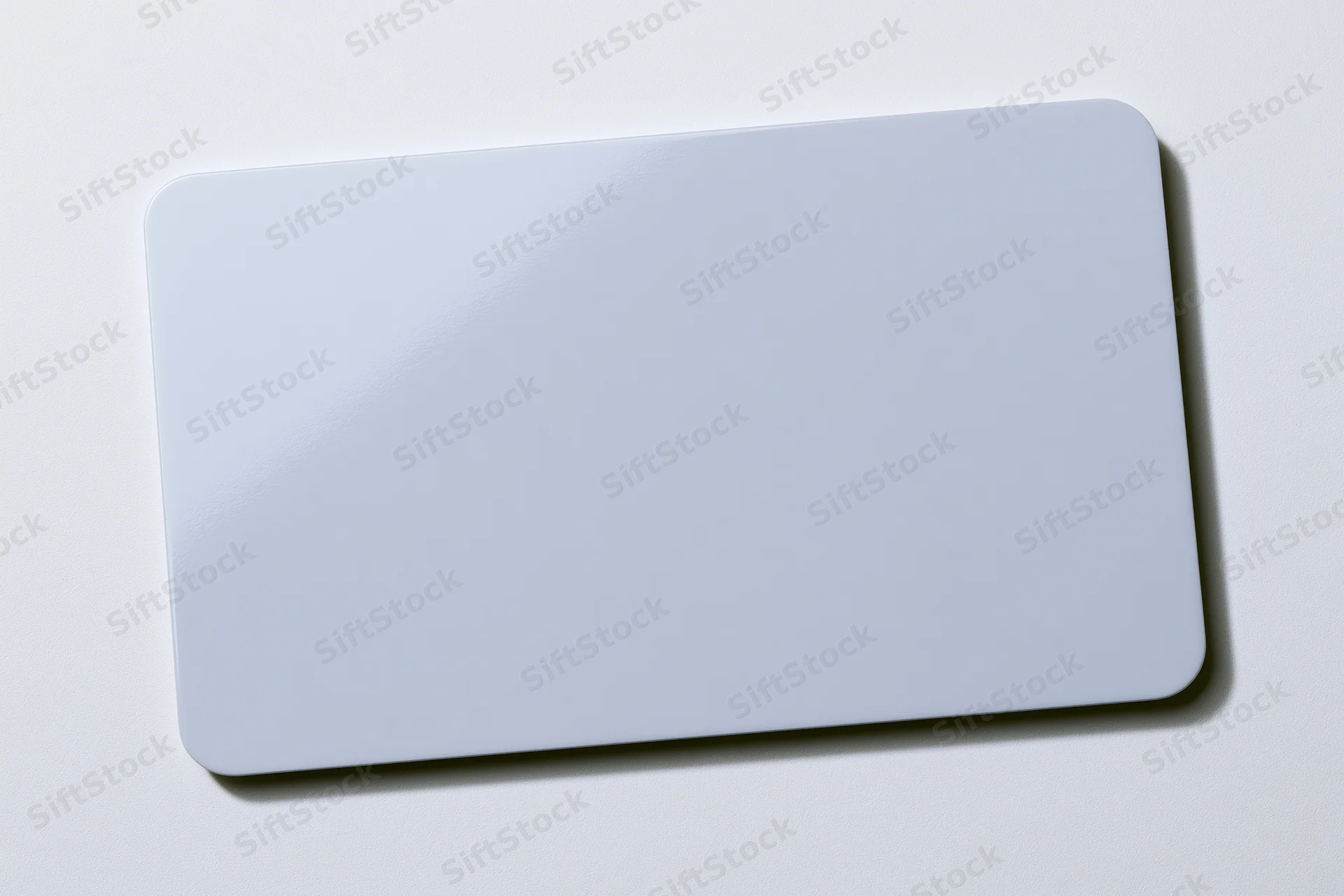 Blank white plastic card lying flat on white surface center