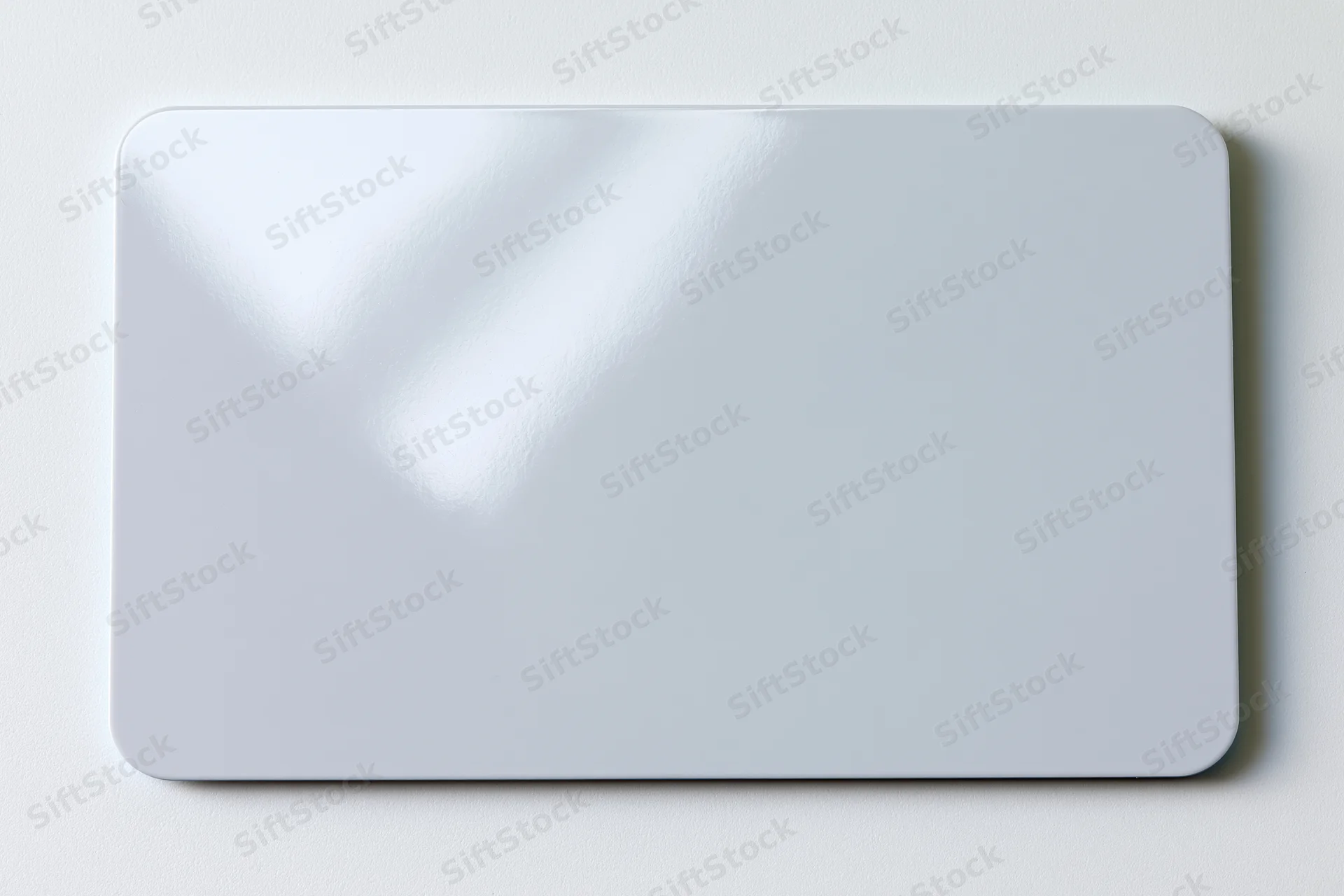 Blank white plastic card lying flat on a white surface center