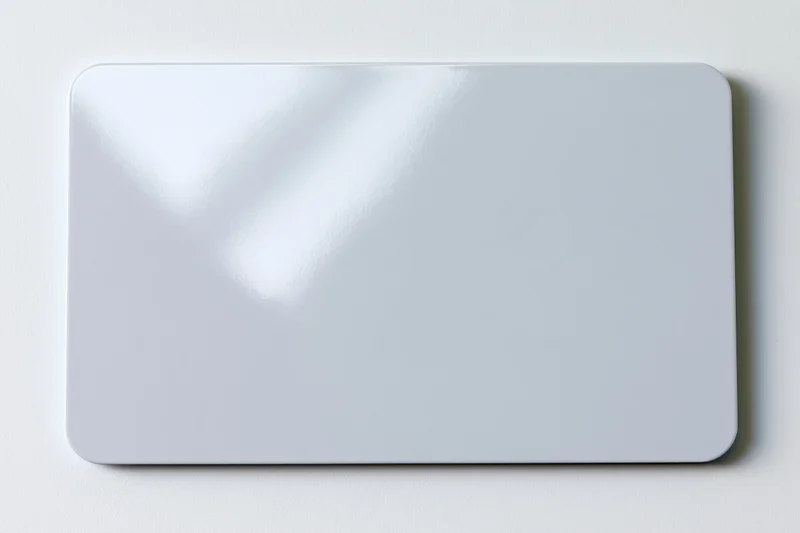 Blank white plastic card lying flat on a white surface center