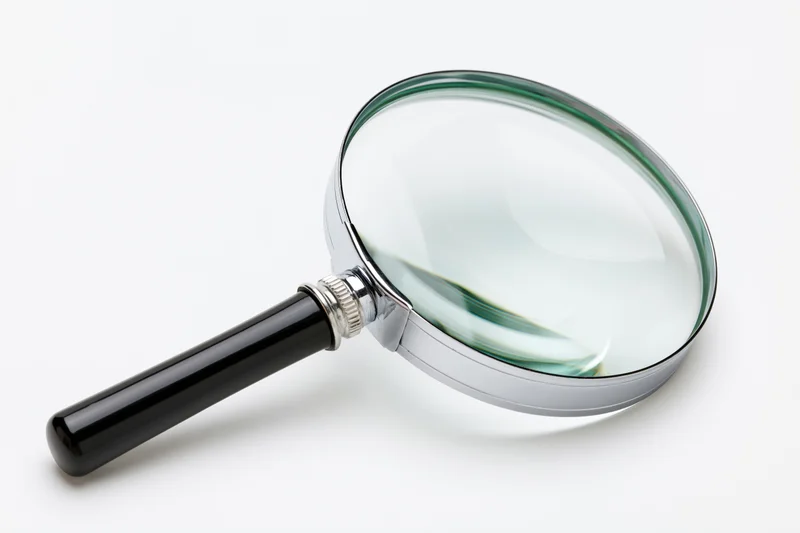 Classic magnifying glass with black handle and silver chrome frame on white background