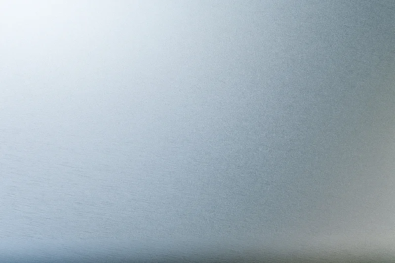 Close-up flat lay of a brushed aluminum surface with subtle texture and gradient lighting