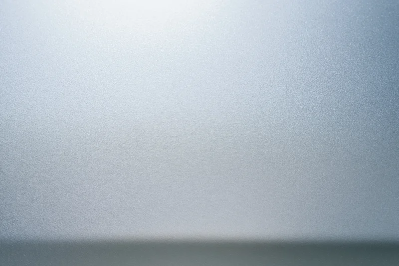 Close-up flat lay of a brushed aluminum or frosted glass surface with smooth texture and light gradient