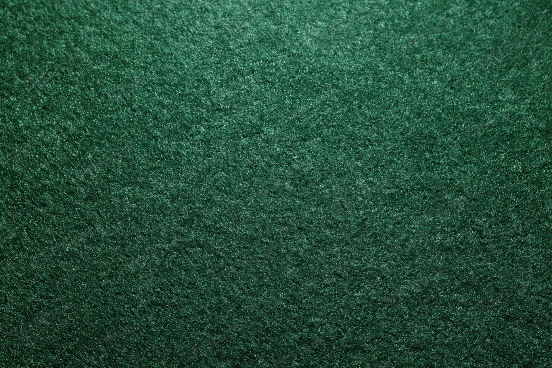 Close-up flat lay of dark forest green felt or suede fabric surface