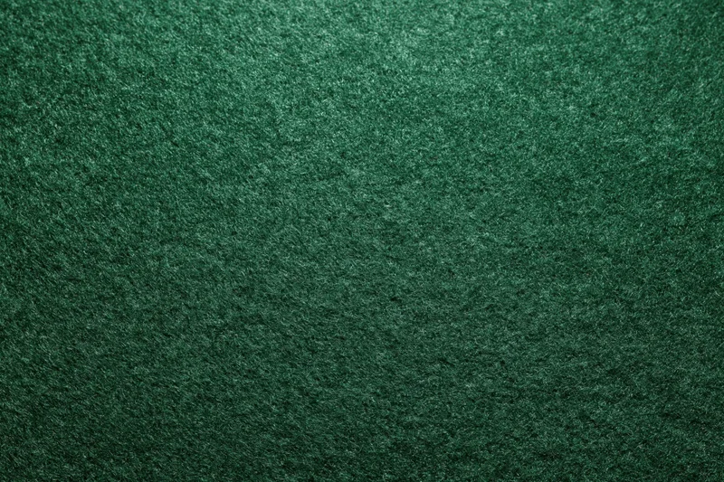 Close-up flat lay of dark forest green felt or suede fabric surface